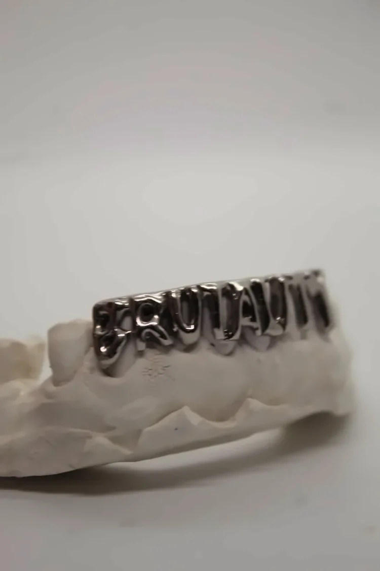 Pieza de plata pulida con letras, montada sobre el molde de yeso